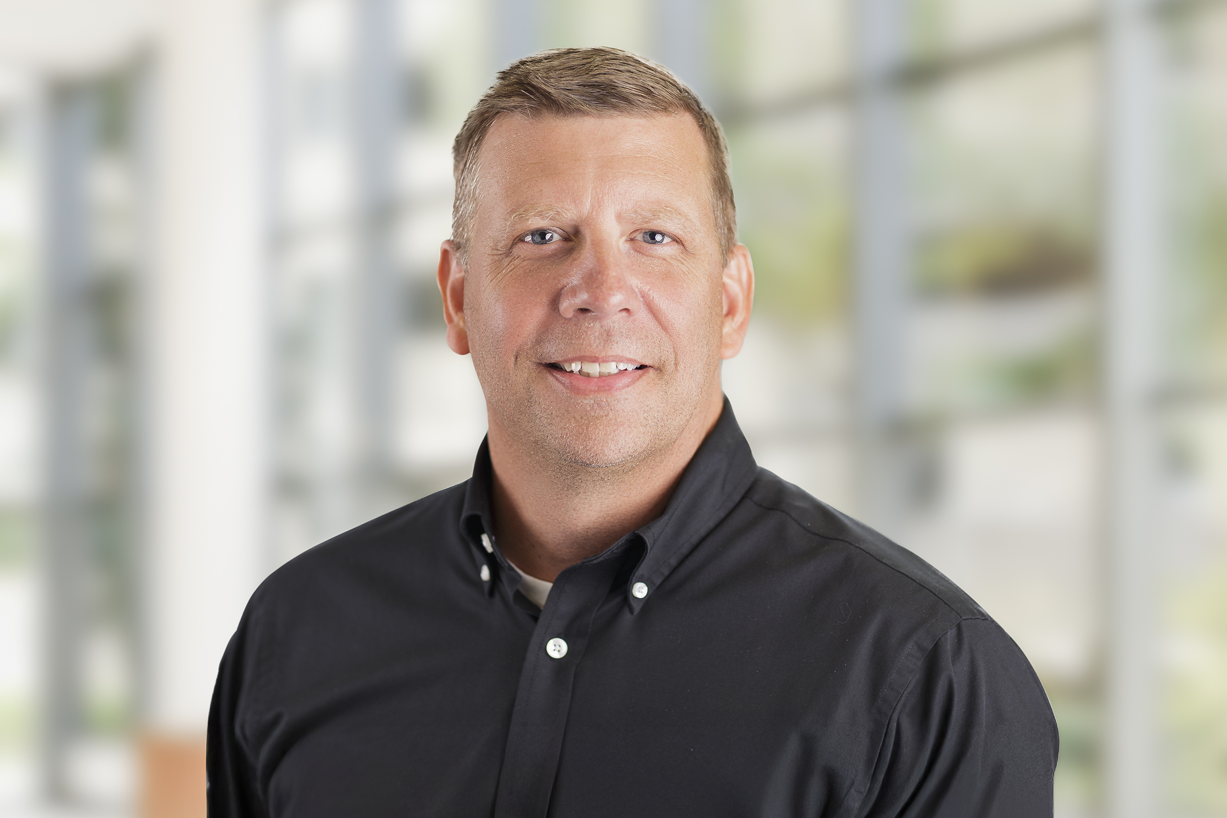 Professional headshot of Johnny Walker smiling against a neutral studio backdrop.