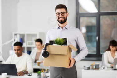 man holding box full of office supplies and decor