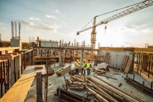 Construction site with three engineers and crane on the top of new skyscraper