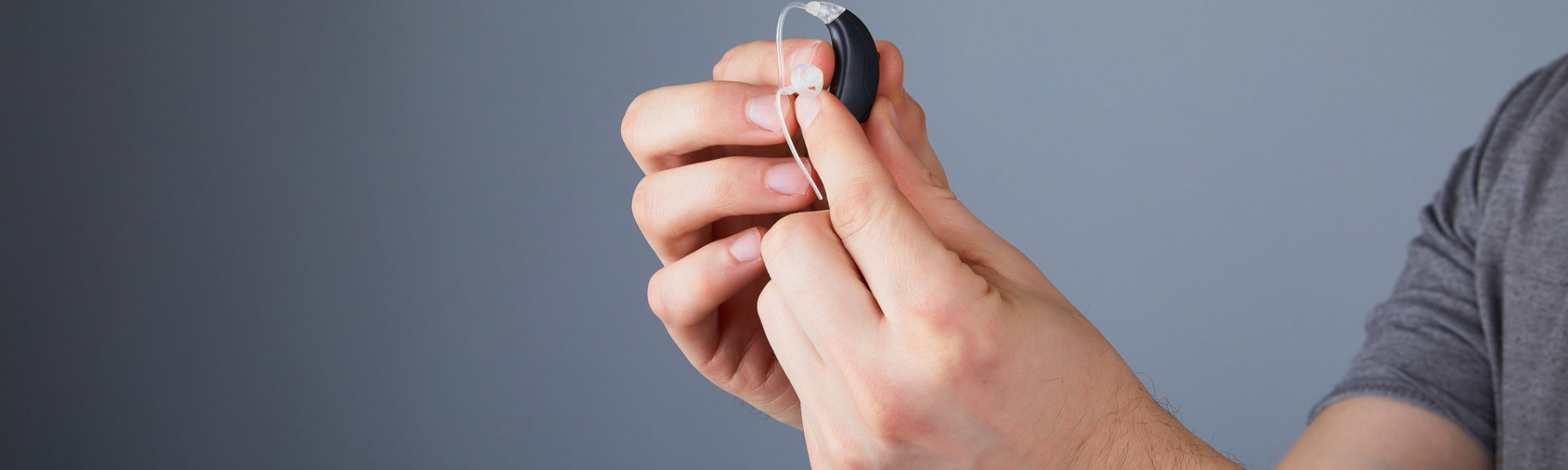 holding small black hearing aid