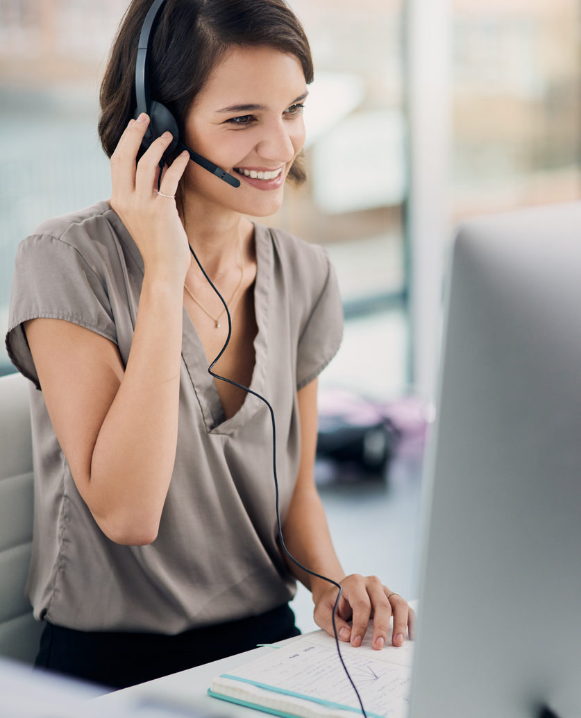 woman using a headset while sitting at her desk in the office