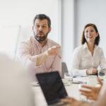Businessman with beard explaining in meeting with colleagues