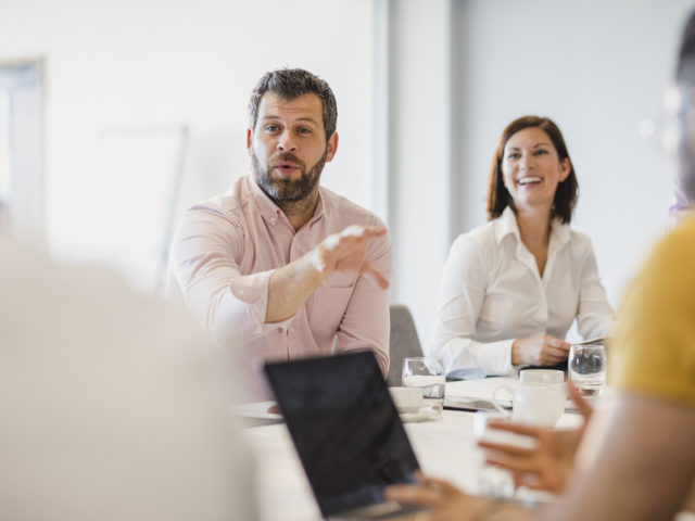 Businessman with beard explaining in meeting with colleagues