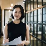 Cheerful businesswoman in her 30s with paperwork