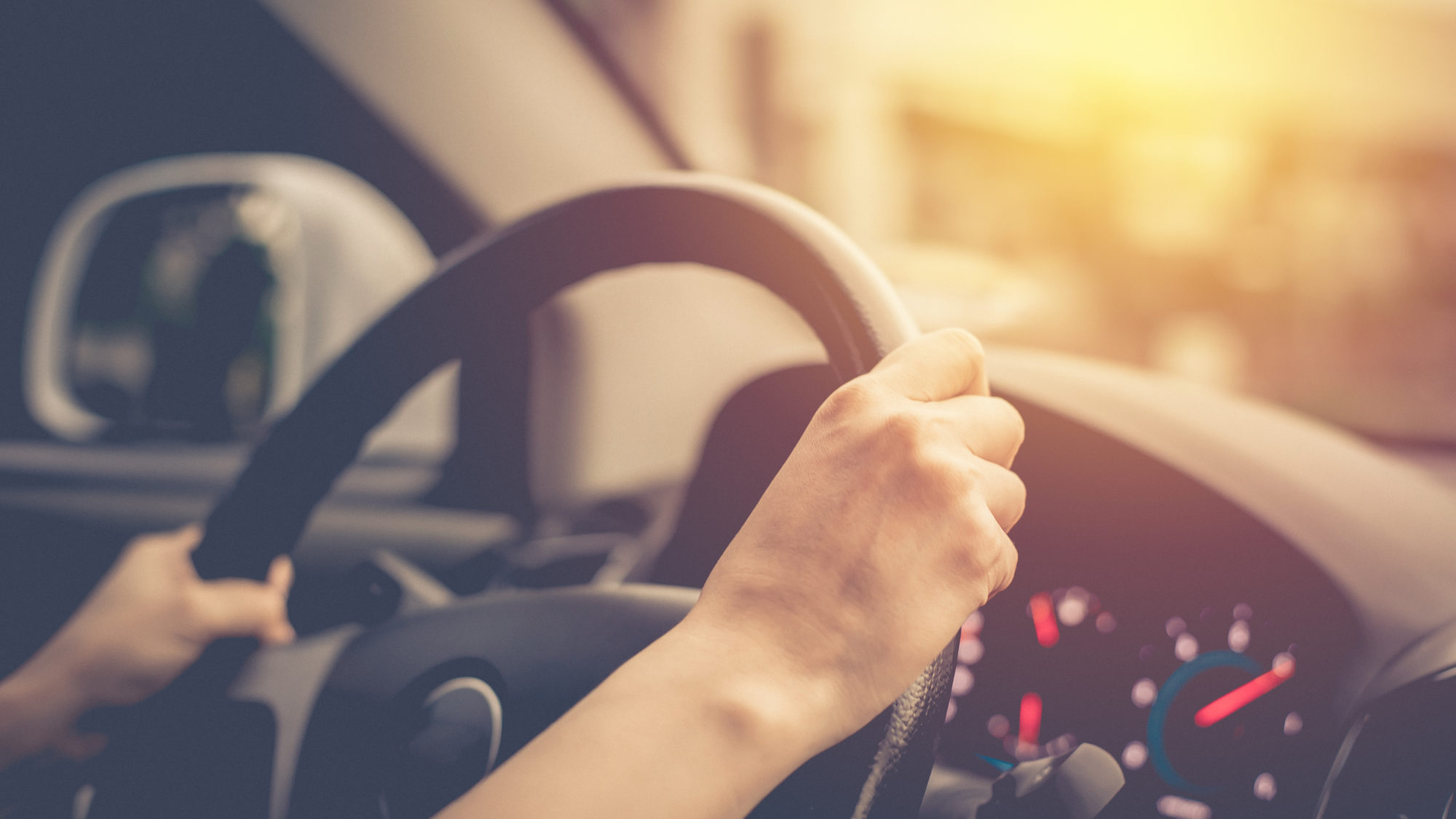 female hands on steering wheel of car