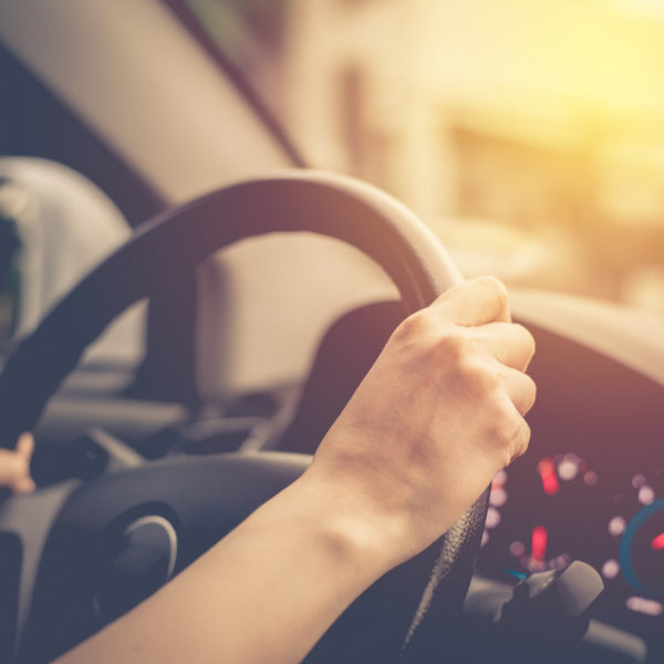 female hands on steering wheel of car