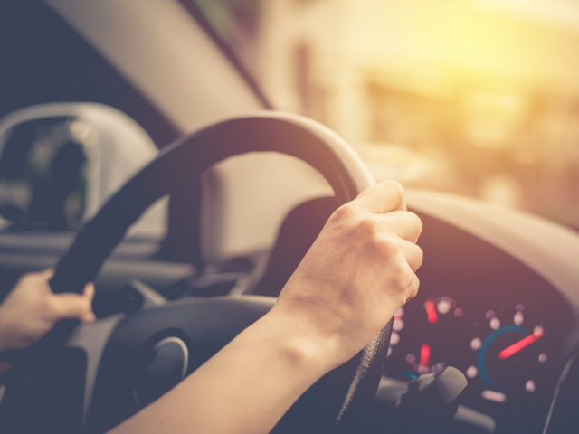 female hands on steering wheel of car