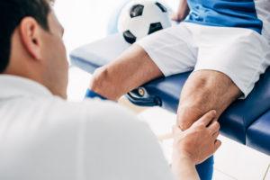 doctor examining soccer player's knee