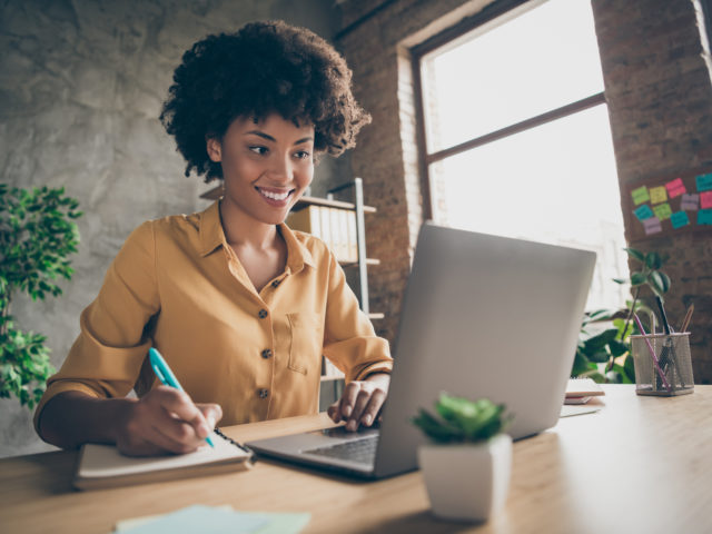 black women taking notes during virtual training on laptop