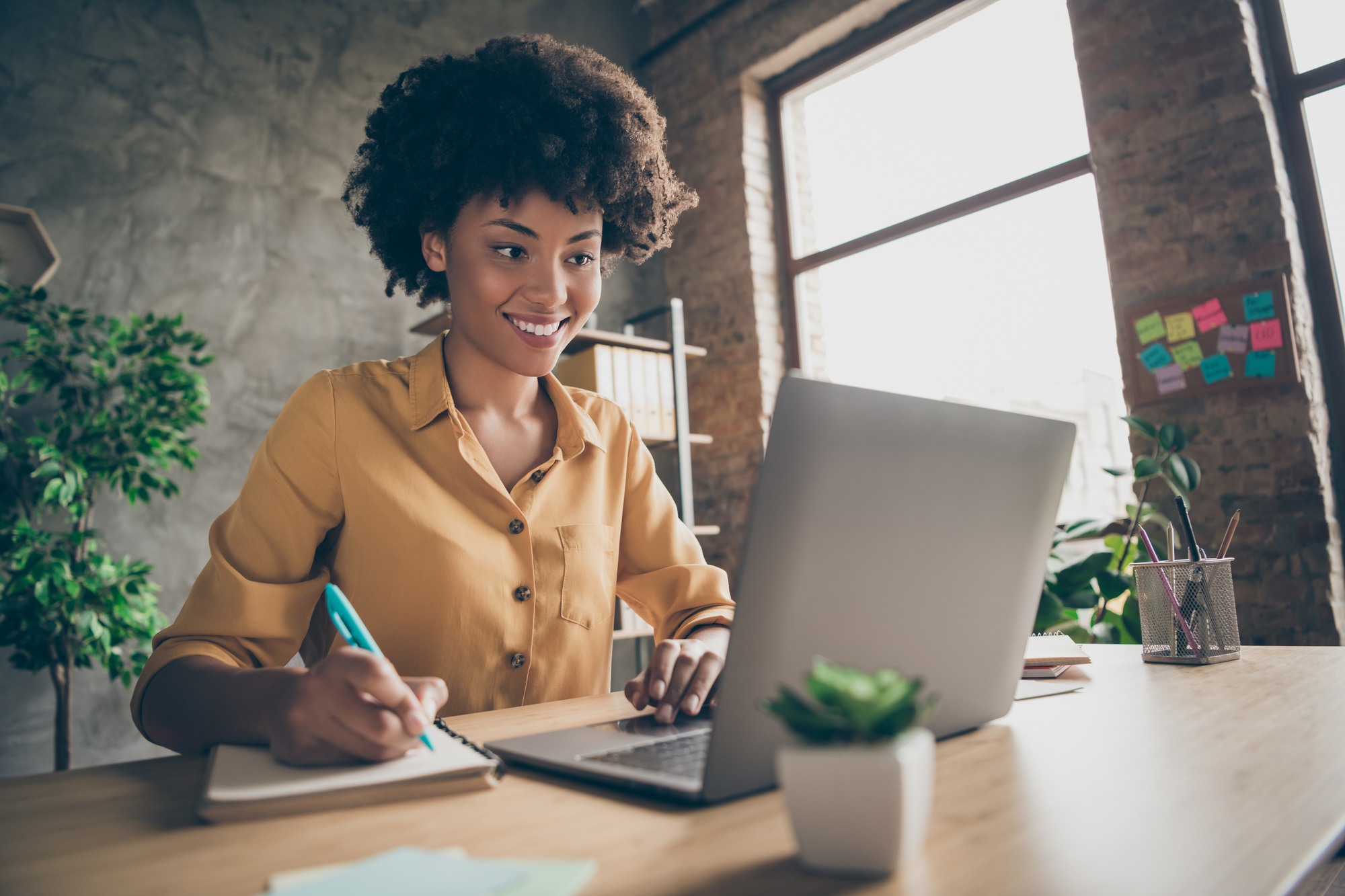 black women taking notes during virtual training on laptop