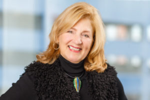 Professional headshot of Donna Horrigan smiling, set against a neutral studio background.