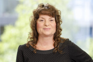 Professional headshot of Pam Lindemann smiling against a simple studio background.