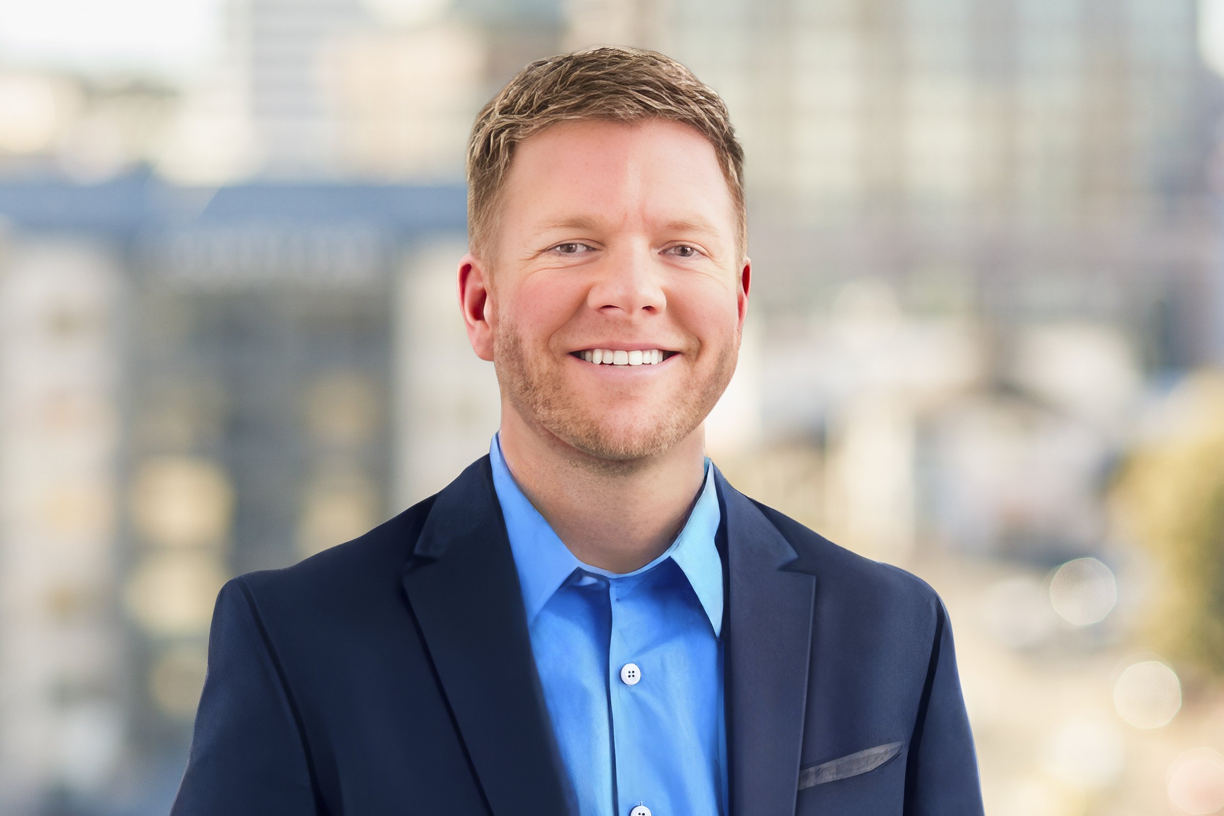 Professional headshot of Danny Jessop smiling, set against a neutral, professional environment.