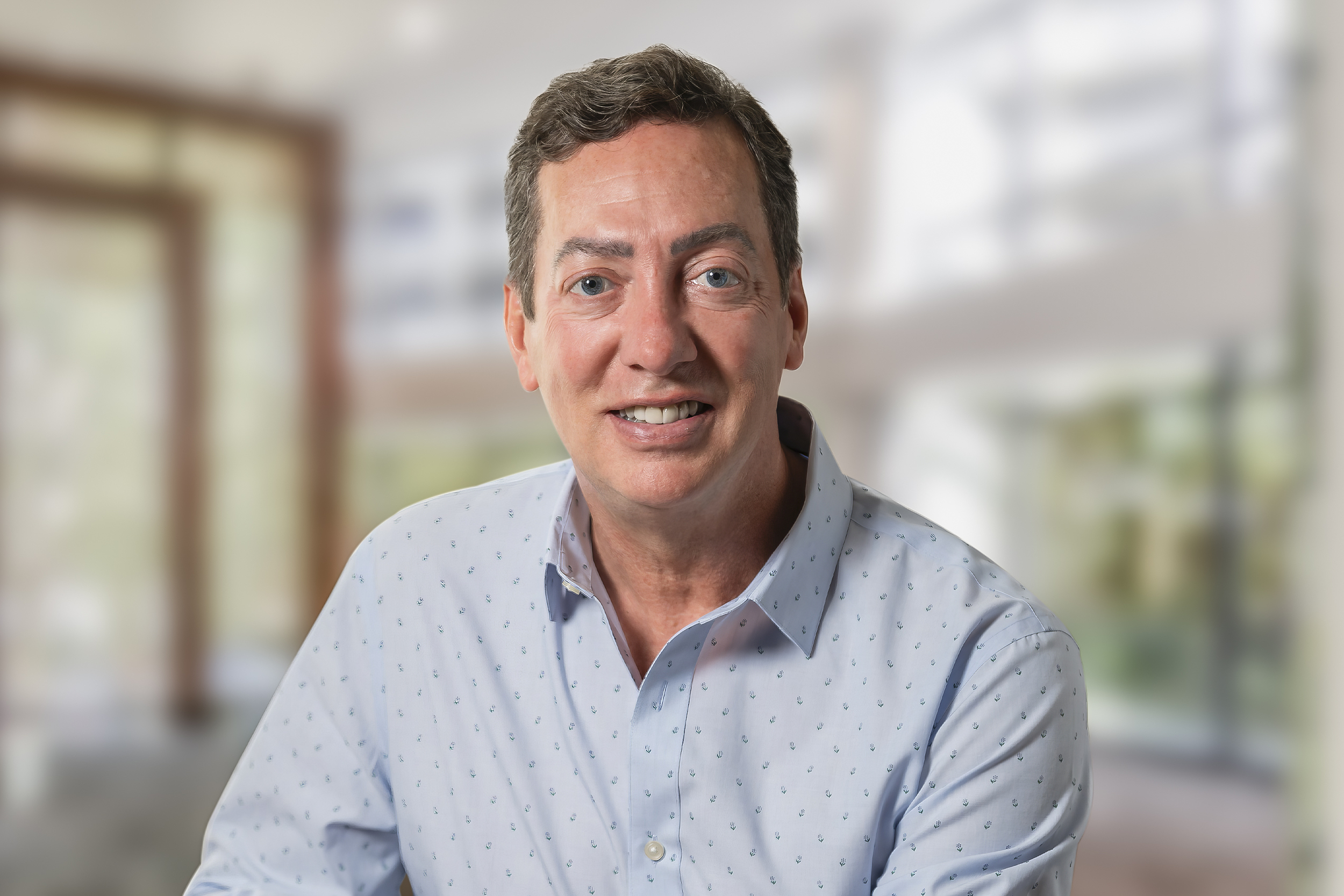 Professional headshot of John Beranek smiling in a modern office environment.