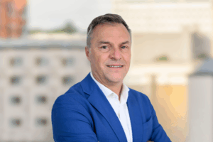 Professional headshot of George smiling in a clean and modern corporate portrait.
