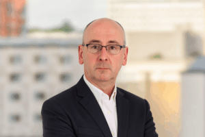Professional headshot of AJ Jones smiling, positioned against a clean, neutral background.
