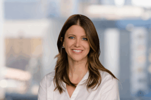 Professional headshot of Emily Mason smiling against a neutral studio backdrop.